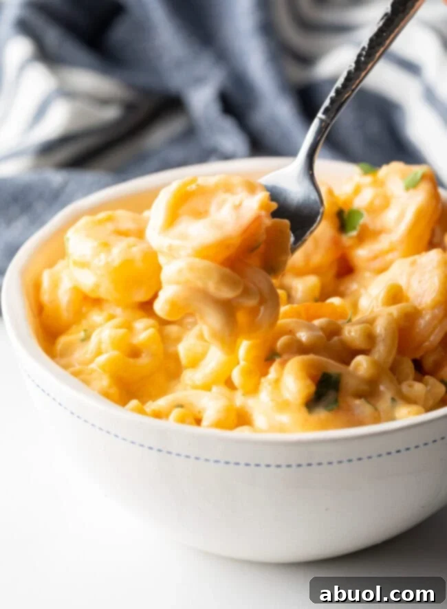 Bowl with serving of shrimp mac & cheese, fork taking a bite from the bowl.