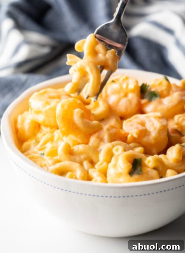 Fork taking bite of macaroni with cheese from bowl.