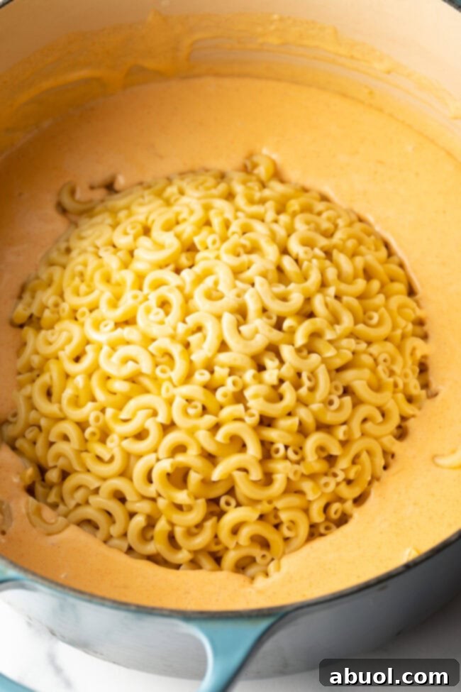Drained noodles added to the pot with cheese sauce.