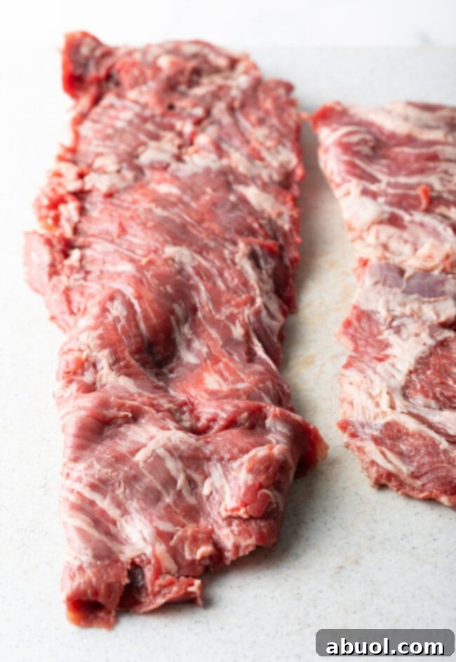 Raw skirt steak on white cutting board