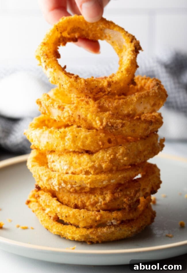 Hand adding onion ring to stack of air fried rings.
