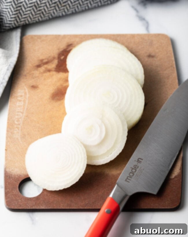 Sliced onions on a cutting board with a knife.
