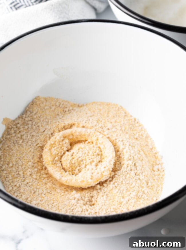 Onion ring in a bowl with breading mixture.