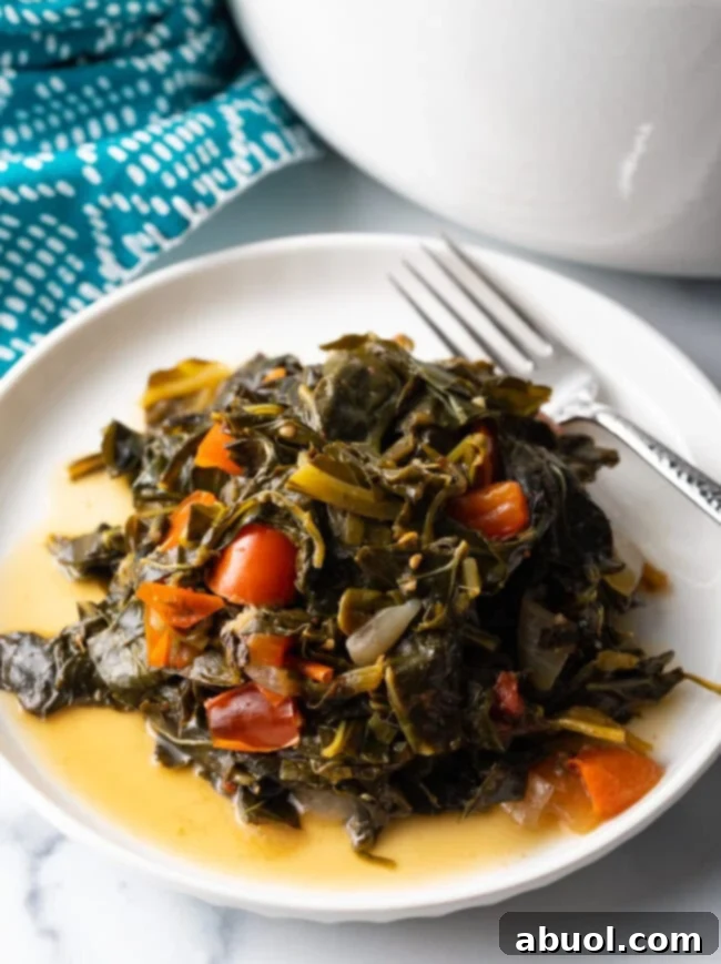 Close view plate of Jamaican greens with tomatoes, fork to the side of the plate.