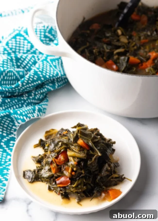 White plate with serving of stewed collard greens with tomato.