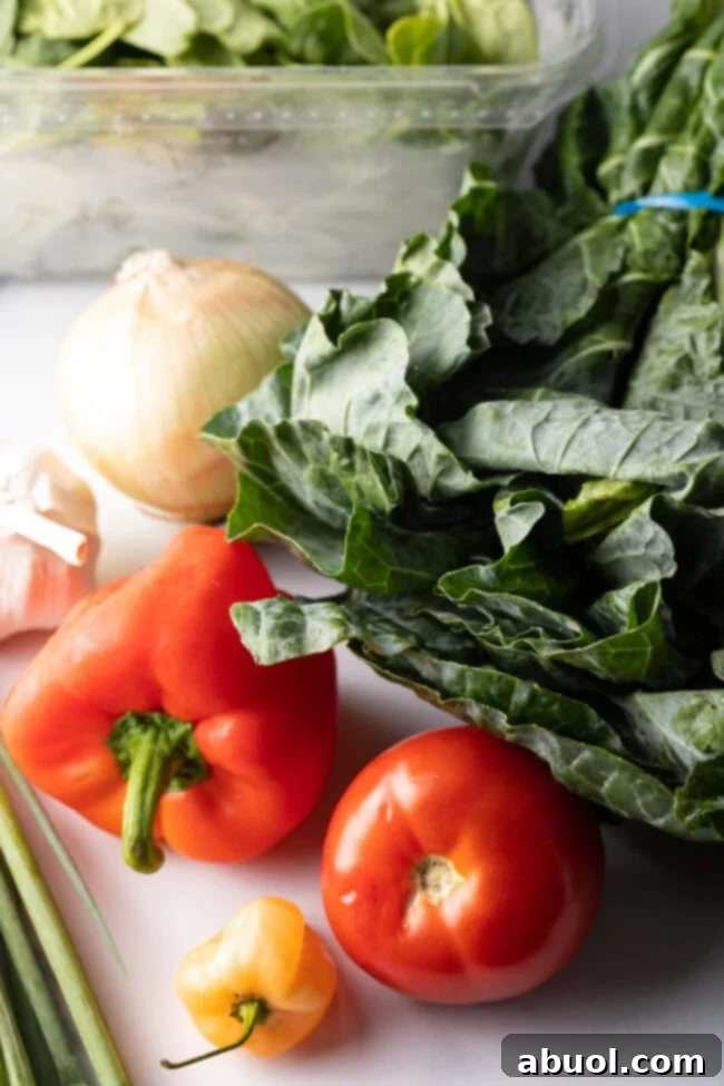 Recipe ingredients on a white background: Tomato, red bell pepper, habanero pepper, scallions, fresh collard greens, garlic, white onion.