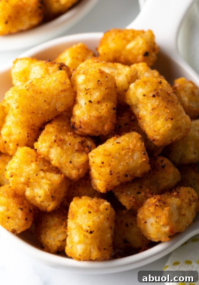 Close-up view of a single, perfectly golden and crispy air-fried tater tot, highlighting its appetizing texture.