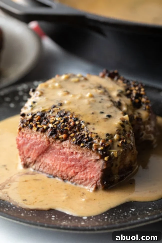 Close-up view of a perfectly cooked Steak au Poivre, showing the juicy medium-rare interior and thick peppercorn crust.