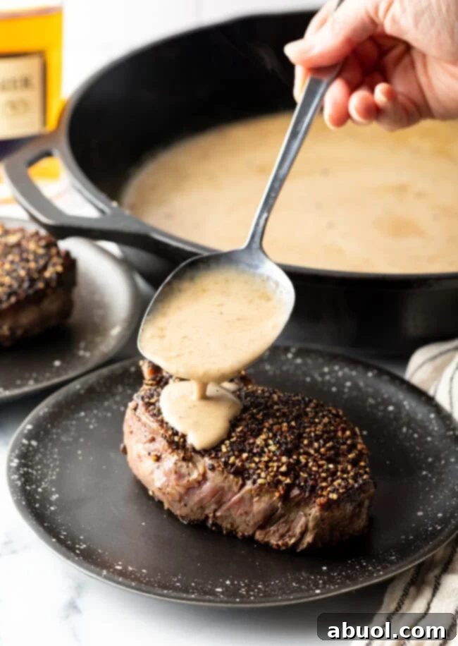 A hand carefully spooning a rich cognac steak sauce over the tender meat on a plate, creating an irresistible presentation.