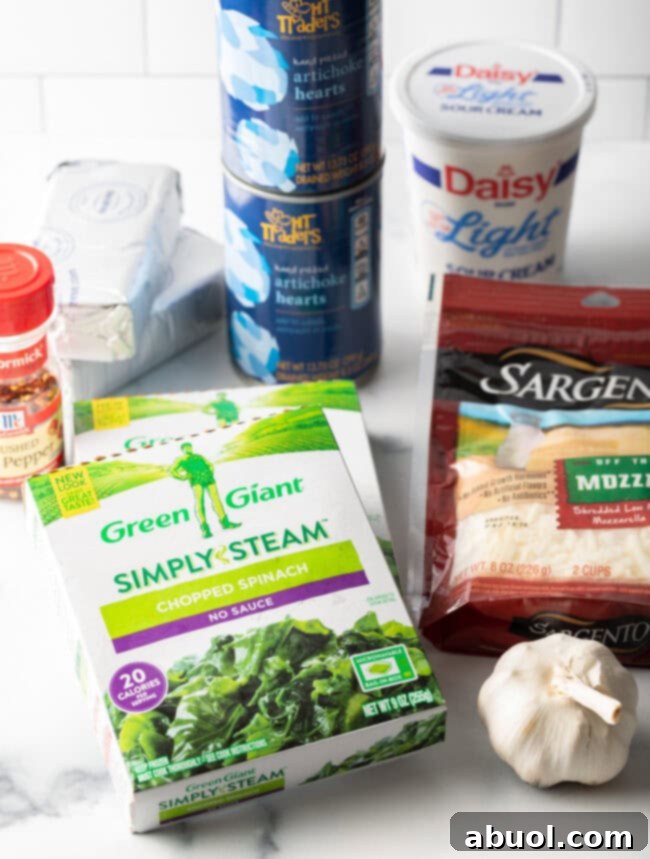 Ingredients laid out for Crockpot Spinach Artichoke Dip on a clean white background.