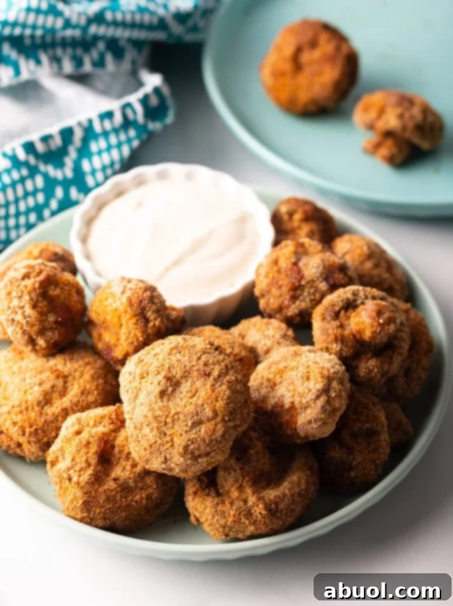 Air Fryer Mushrooms - Plate overflowing with fried mushrooms with sauce in a ramekin.