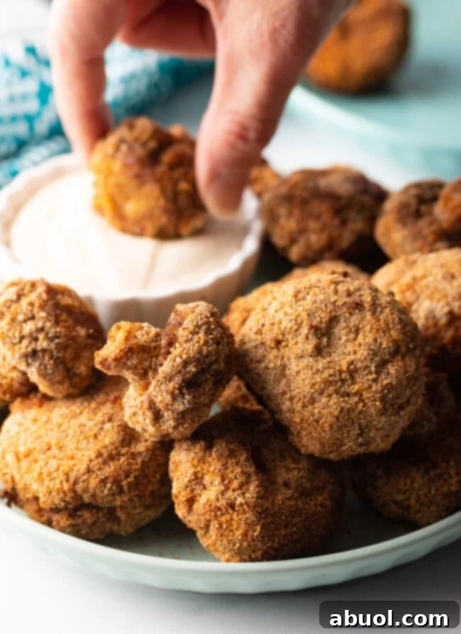 Hand dipping a crunch air fried mushroom into dressing.