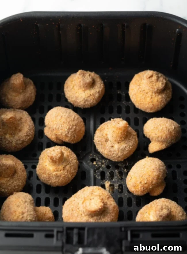 Battered mushrooms in the air fryer basket.