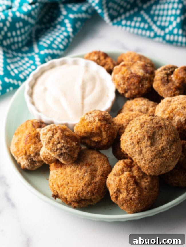 Air fryer mushrooms on a plate with ramekin of sauce.