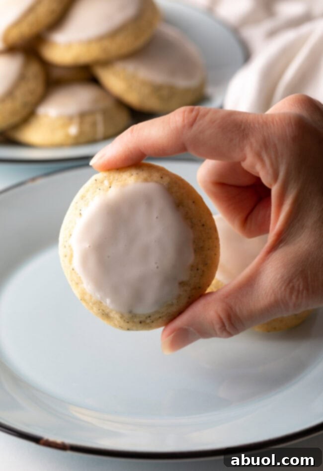 Hand holding a freshly dipped Earl Grey cookie towards the camera.