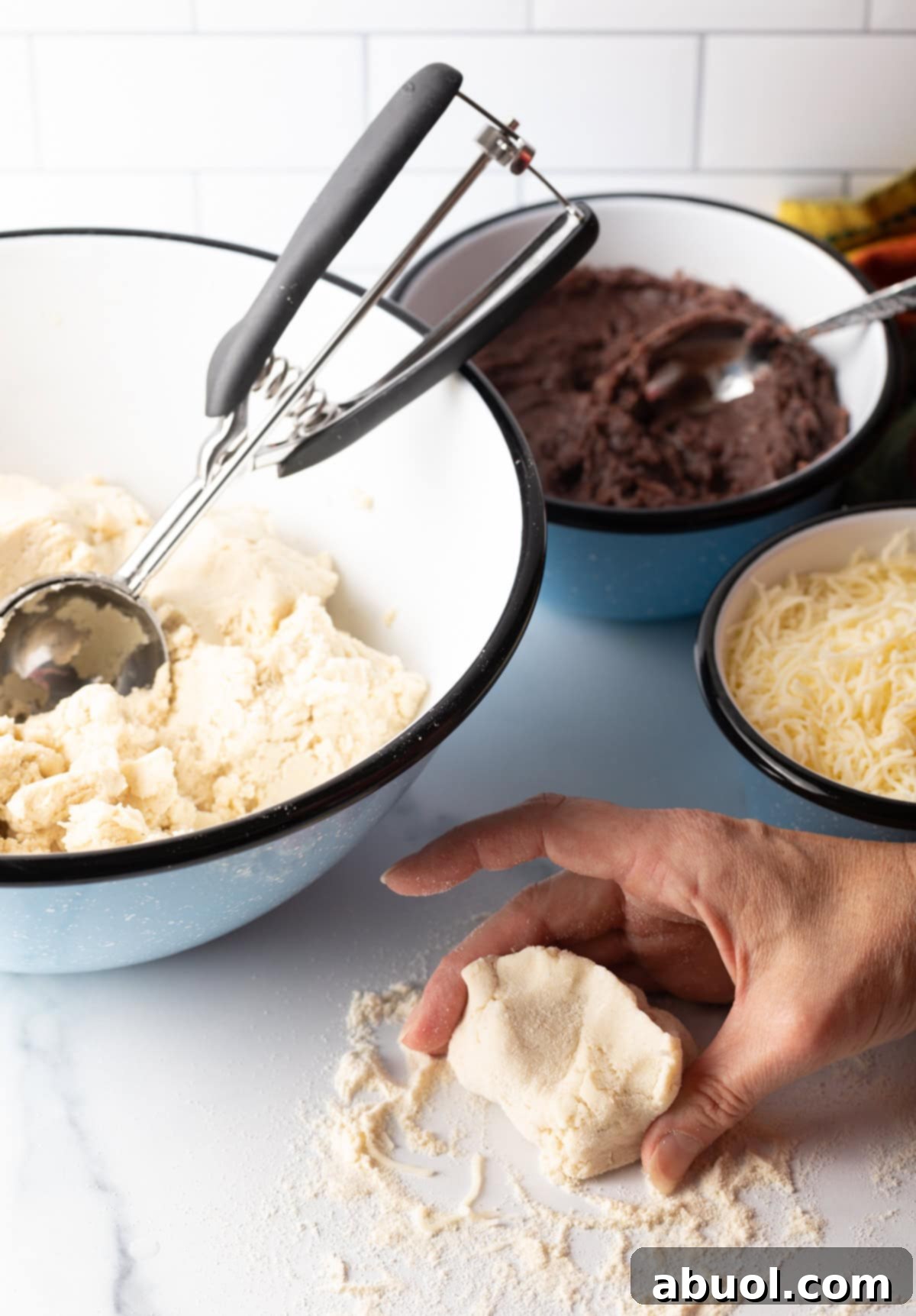 A hand continuing to shape and smooth the dough, forming a perfectly sealed ball.
