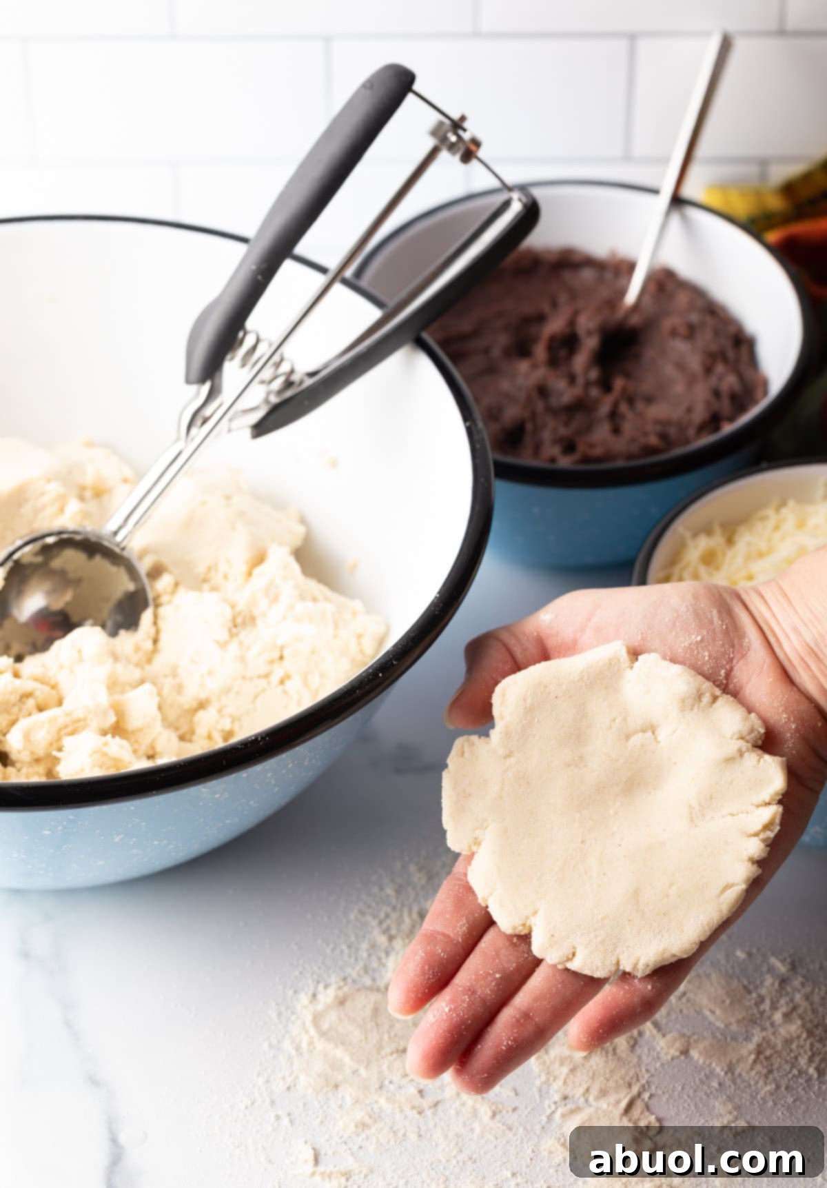 A hand expertly holding a flattened disk of pupusa dough, prepared for filling.