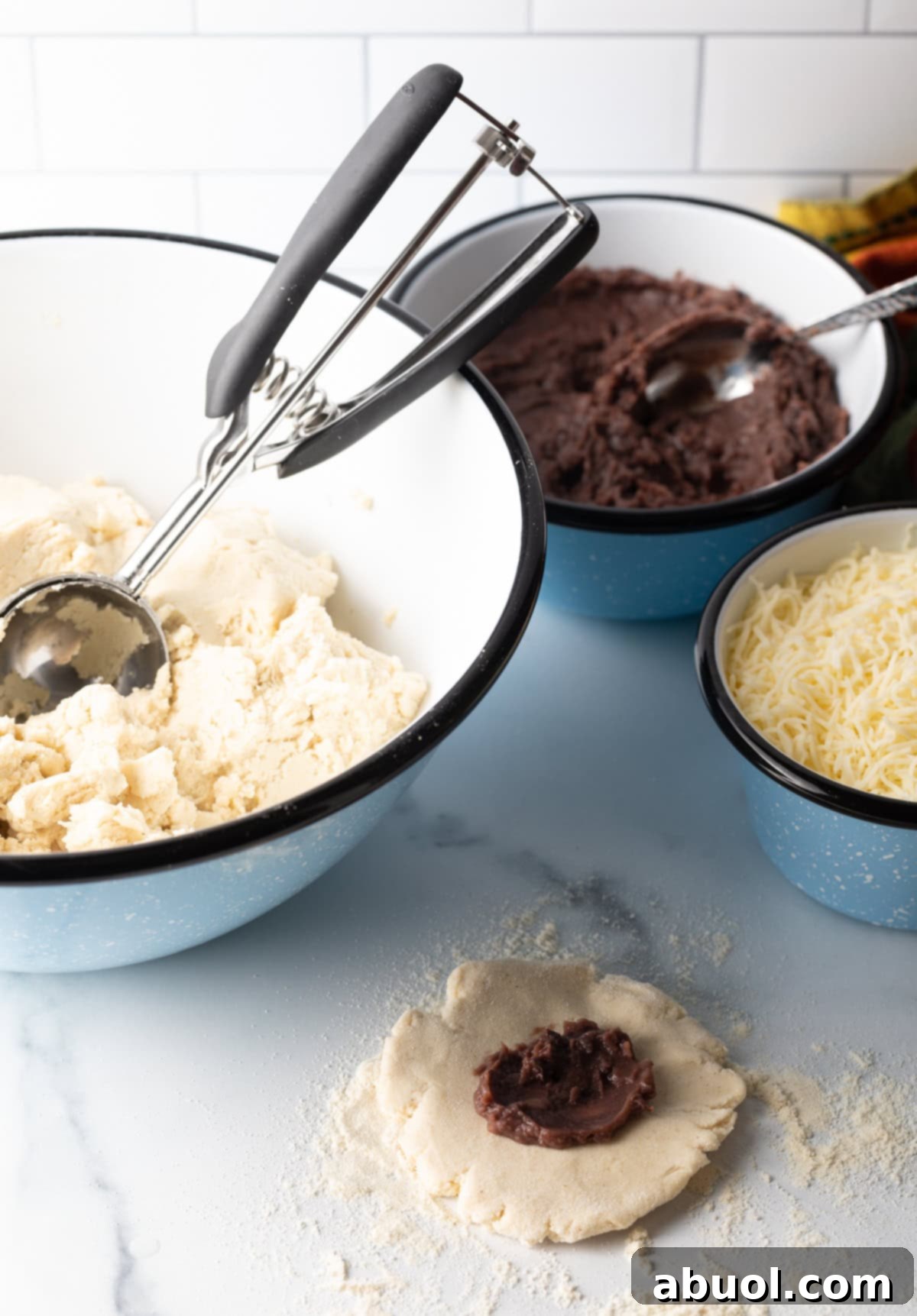 A teaspoon of refried beans carefully placed in the middle of a flattened pupusa dough disk.