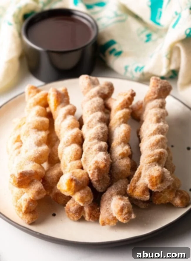 A beautifully arranged plate of golden-brown cinnamon twists, stacked invitingly.