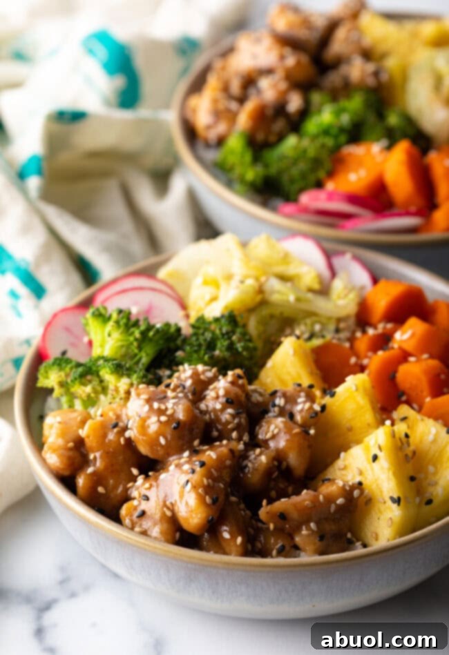 Chicken teriyaki bowl with pineapple, carrots, broccoli, cabbage, and radishes.