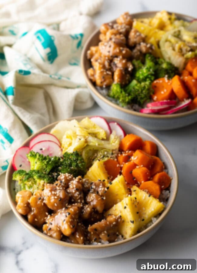 Two bowls with chicken teriyaki, cooked veggies, and fresh toppings.