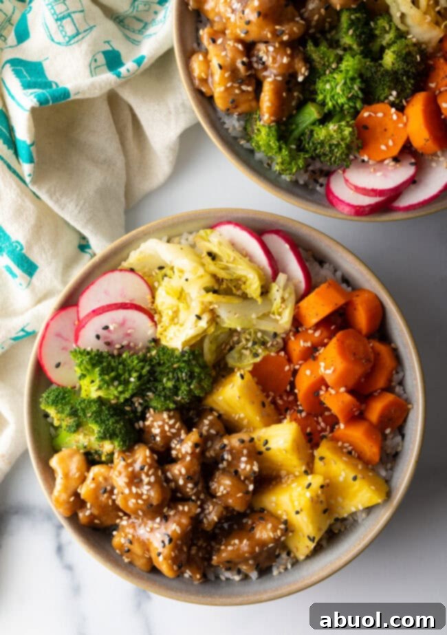 Top down view two bowls loaded with teriyaki chicken, rice, and veggies.