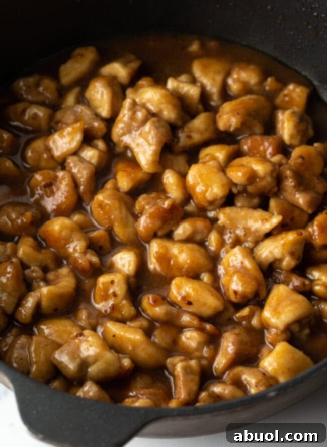 Teriyaki sauce added to the skillet with chicken pieces.