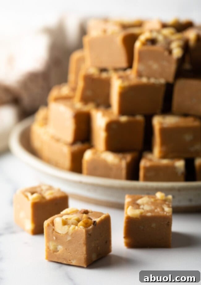 Squares of maple walnut fudge in front of a stack of fudge.