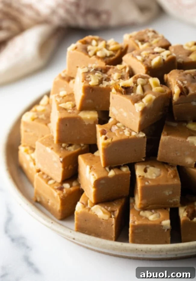 Beautiful plate of maple fudge squares with walnuts stacked up similar to a pyramid.