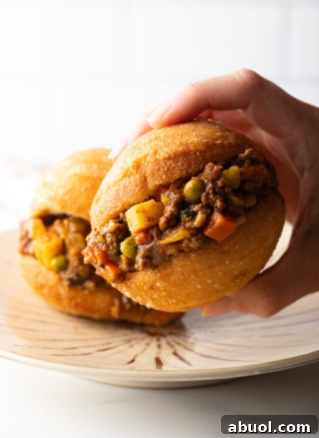 Hand holding fat cake with minced meat filling.