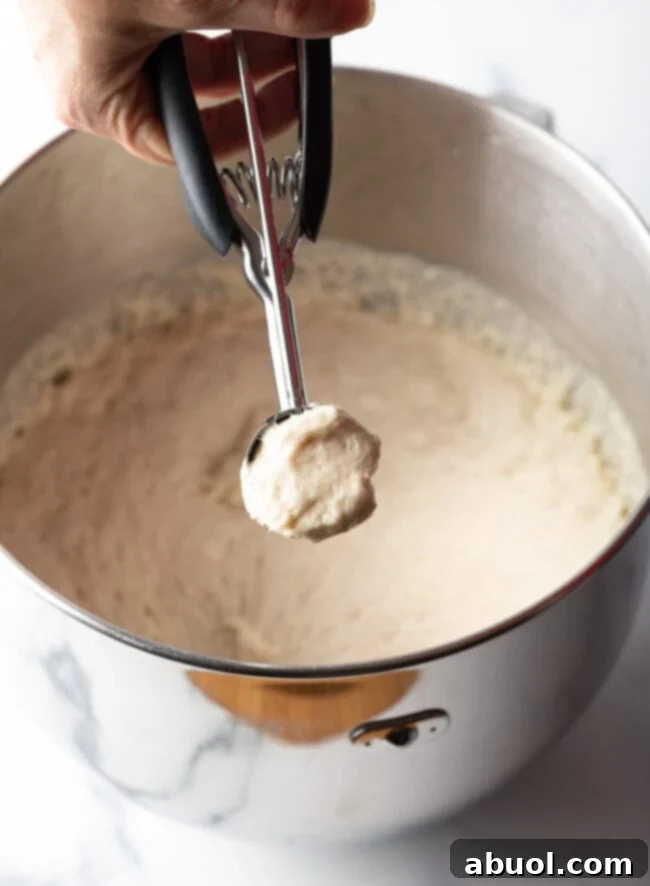 Hand with 2 tablespoon scoop, scooping dough.
