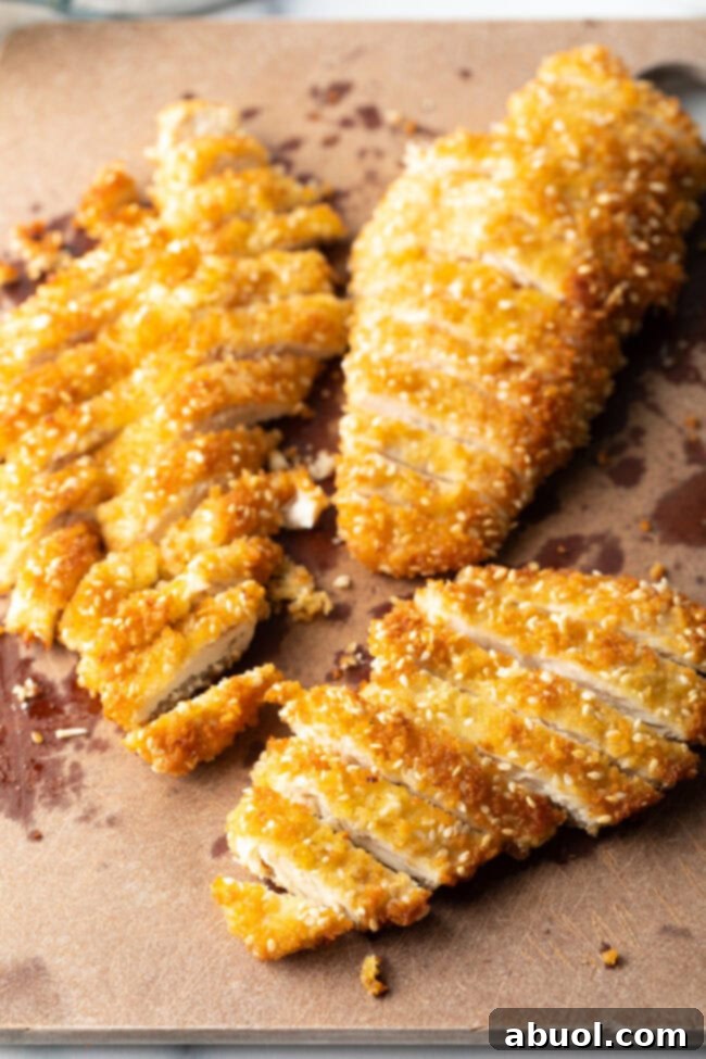 Perfectly sliced chicken katsu strips arranged neatly on a cutting board, ready for serving.