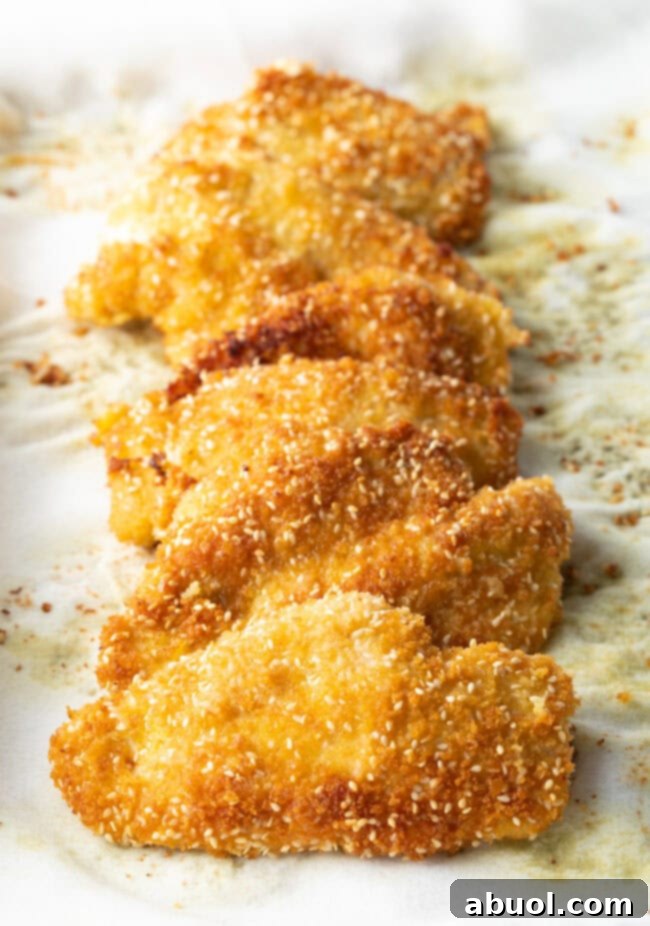 Crispy cooked chicken katsu pieces resting on a paper towel-lined plate after frying, draining excess oil.