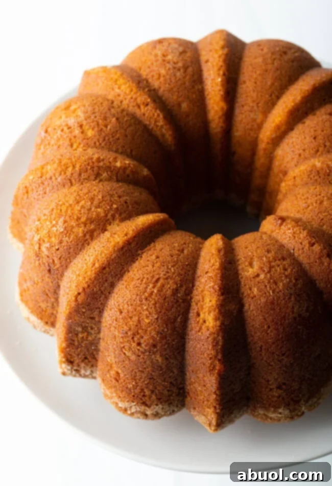 A perfectly baked sweet potato pound cake displayed on an elegant white cake stand, ready to be served for a festive fall celebration.