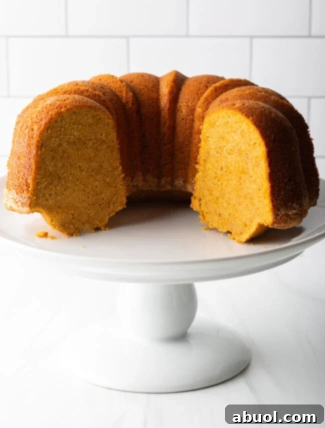 A generous slice of sweet potato pound cake on a white plate, revealing its moist interior, perfect for serving.