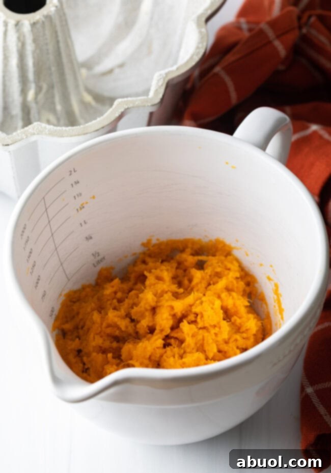 Cooked and smoothly mashed sweet potatoes in a white measuring bowl, prepared for the cake batter.