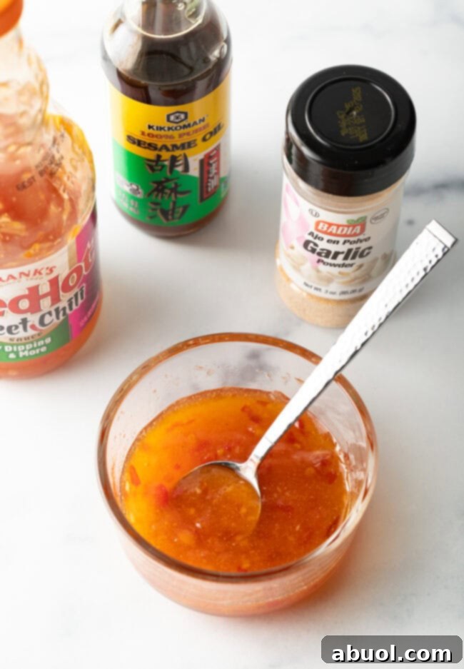 Top down sweet chili sauce in a glass container, adding spices.