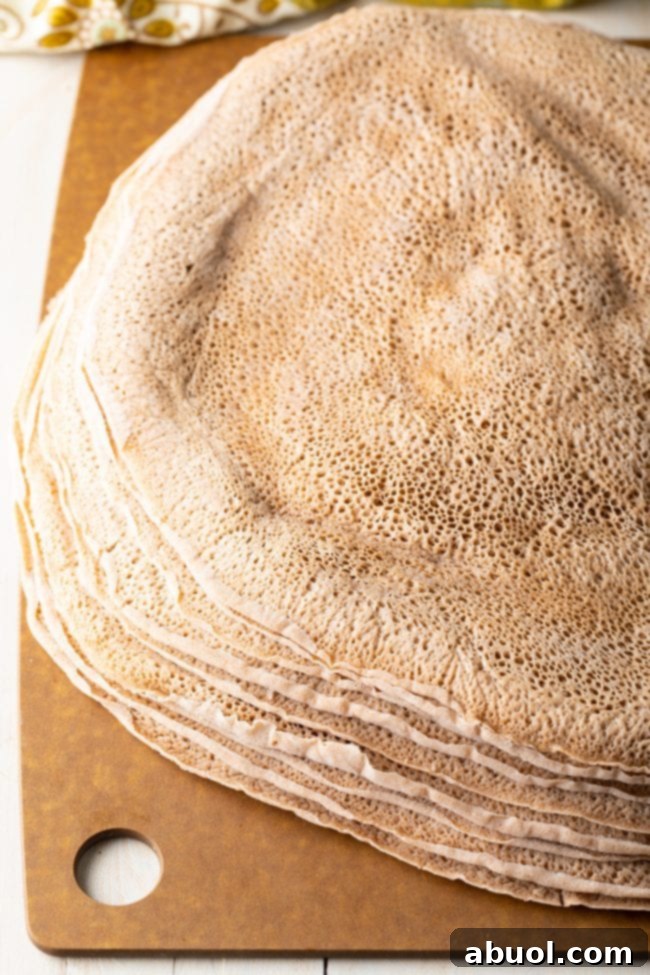 Stacked Ethiopian Injera bread on a rustic wooden surface, highlighting its appetizing visual appeal and readiness for serving.