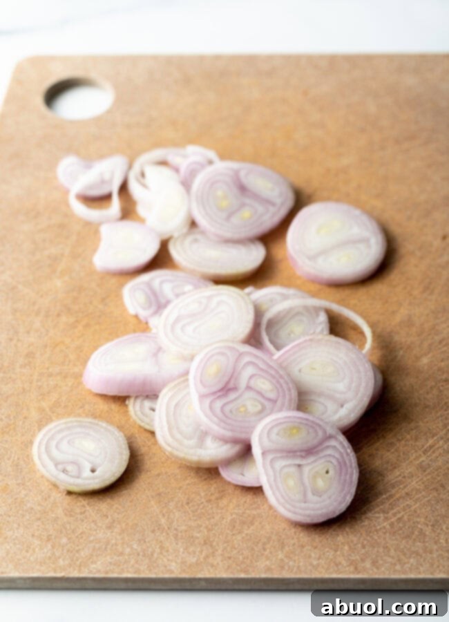 Raw sliced shallots on a cutting board.