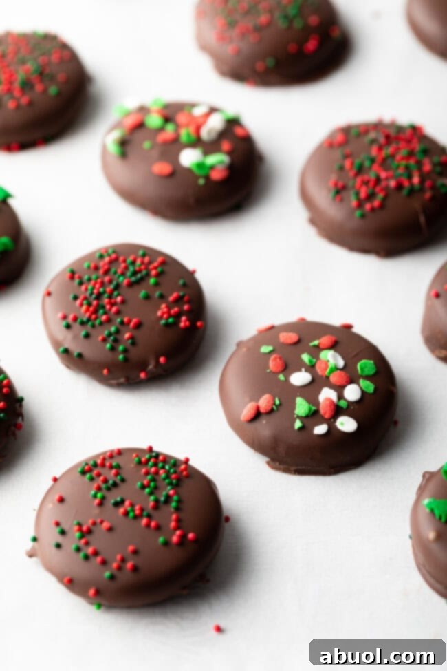 Close view chocolate peppermint candies topped with sprinkles, lines of treats on parchment paper.