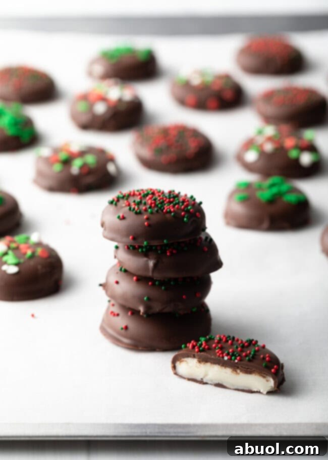 Four peppermint patty candies stacked on top of each other, fifth piece with bite taken out. Rows of more candies in the background.