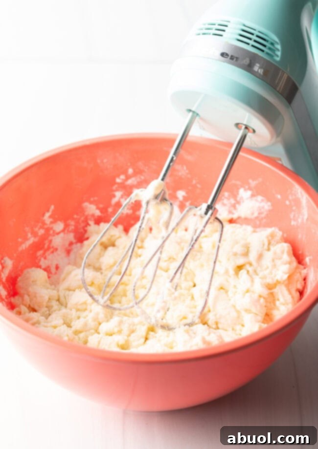 Hand electric mixer and large mixing bowl with ingredients.