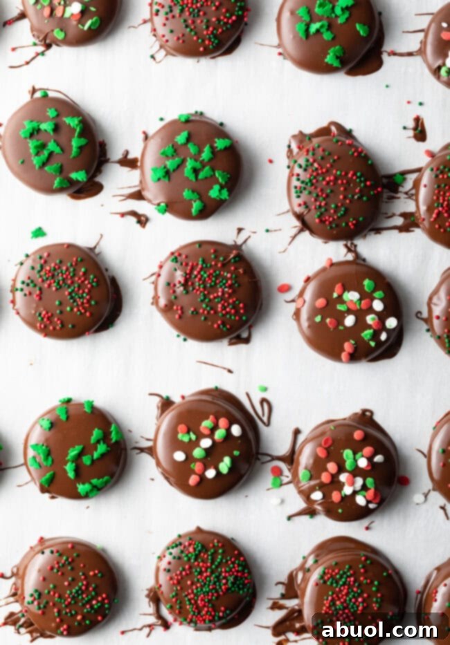 Dipped peppermint patties on parchment paper, sprinkled with green and red candies.