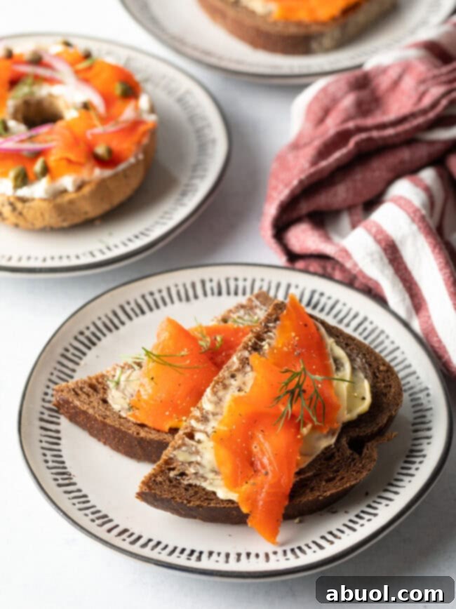 Two slices of hearty pumpernickel bread generously buttered and topped with delicate, thin slices of homemade gravlax, garnished with fresh dill.