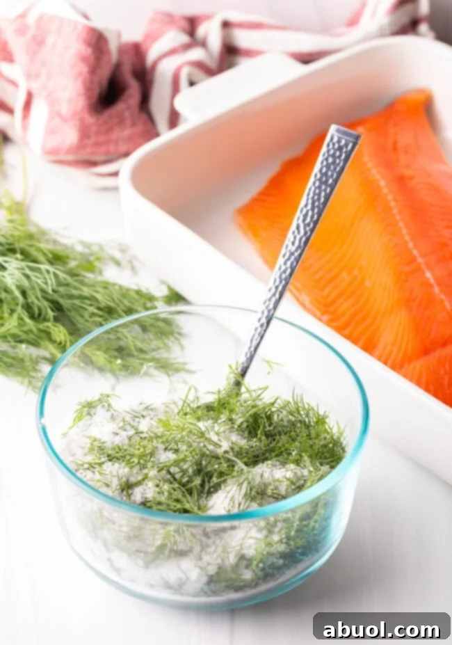 A close-up of fresh dill, coarse kosher salt, and granulated sugar perfectly combined in a small glass bowl, forming the gravlax curing mixture.