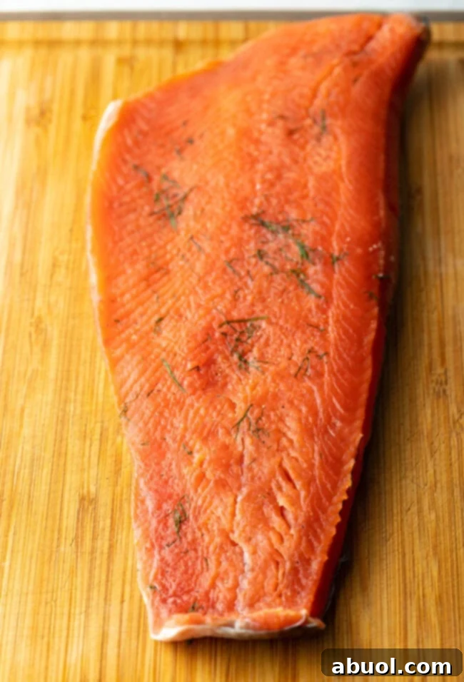 An unwrapped and thoroughly rinsed salmon fillet, now perfectly cured to a tender consistency, displayed on a clean cutting board, ready for the crucial slicing process.