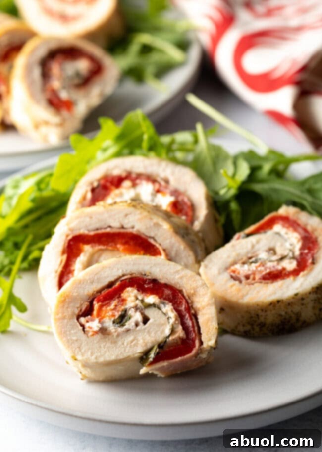 Close up of a plate of sliced chicken roulade with a side of arugula.