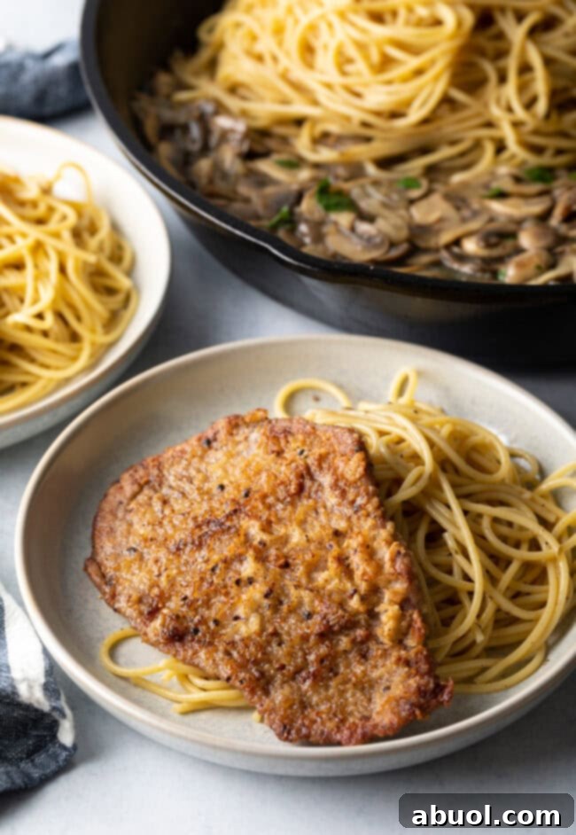 Fried cutlet on a plate of spaghetti.
