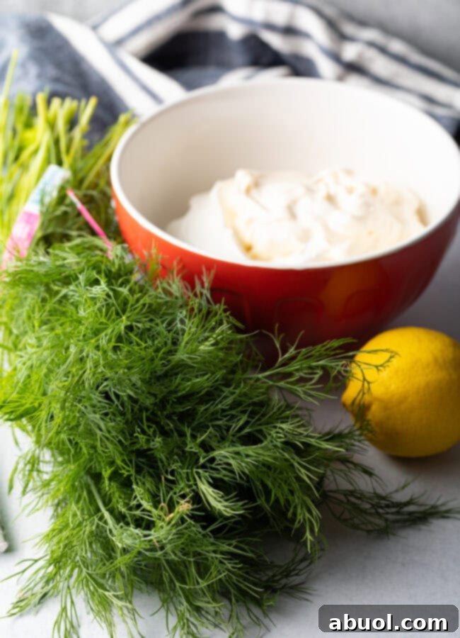 Recipe ingredients: Fresh herbs, whole lemon, bowl of sour cream.