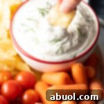 Close up shot of creamy dill dip with fresh dill on top, in a white bowl.